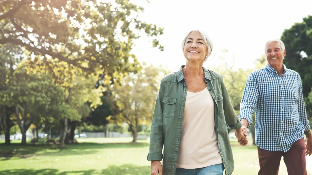 Elderly couple holding hands and walking in a park