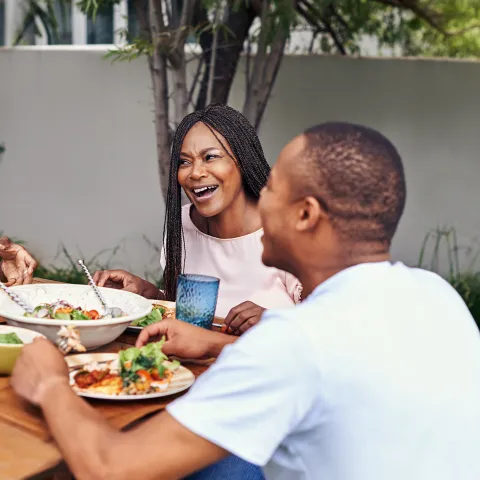 A Family Gathers Around a Outdoor Table to Enjoy a Meal.